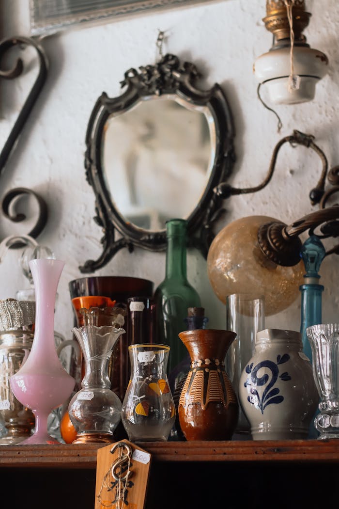 services-04 An assortment of vintage vases, antique mirror, and rustic lamps on a shelf, showcasing timeless elegance.